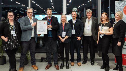 A group of professionals posing together after receiving award, showcasing their accomplishment at a formal event.