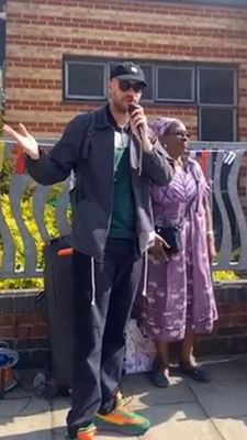 Two people stood together. One is slightly in front and has a microphone upto their mouth