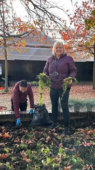 Two volunteers working on a planter. They are holding plants in their hands and working through the soil.