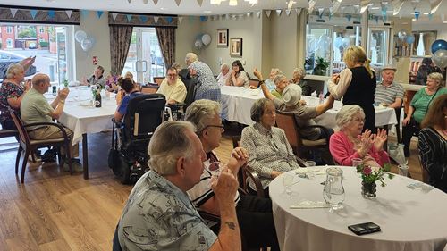residents and colleagues sat in room around round tables celebrating the anniversary