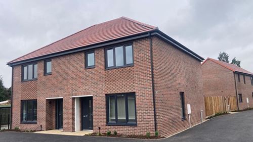 South Buck home area after. Newly constructed two-story brick duplex with black-framed windows and red-tiled roof